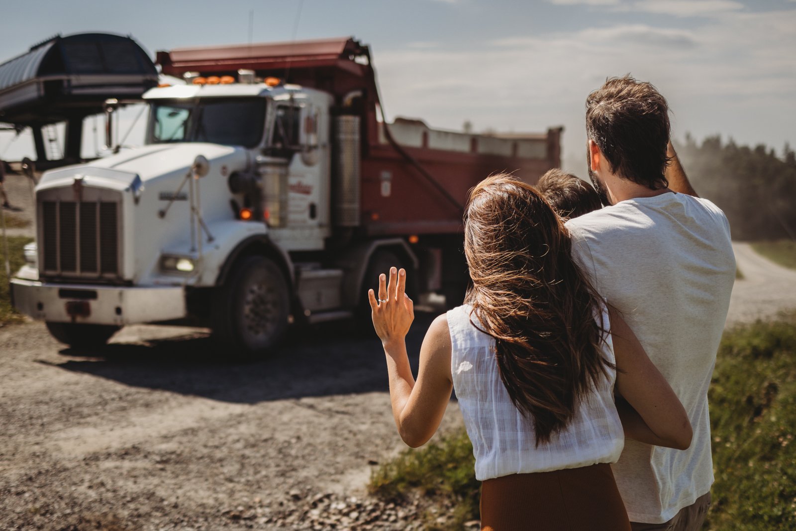 mom, dad, and son waving at a construction truck